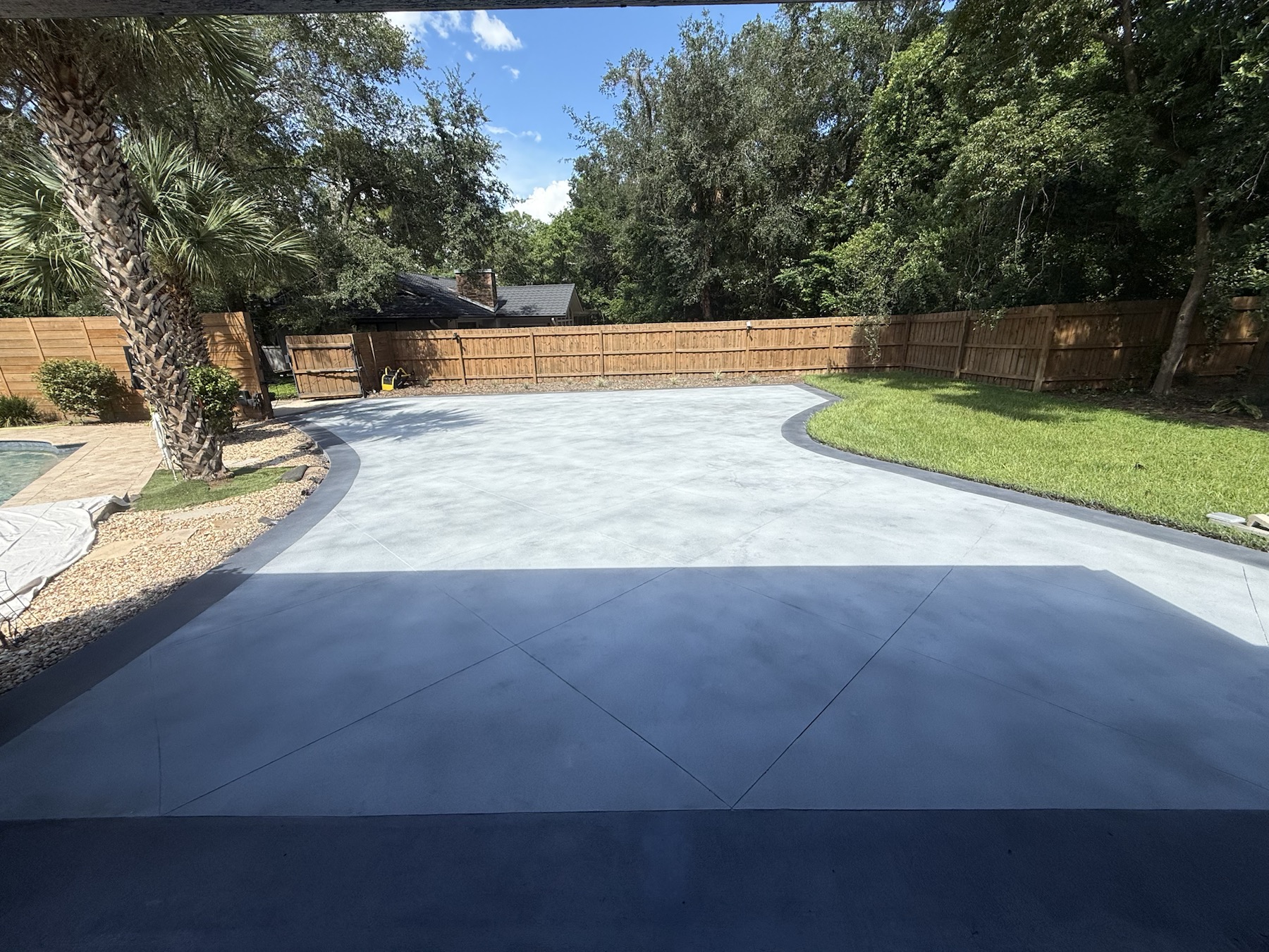 Driveway resurfaced with a light gray PetraReGen finish, dark borders and decorative control-line detailing