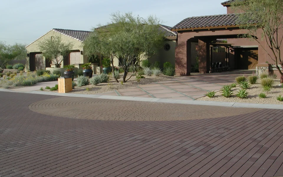 Decorative patterned asphalt with a circular accent in a landscaped plaza; an Asphatec family example, not a confirmed AsphaStamp installation