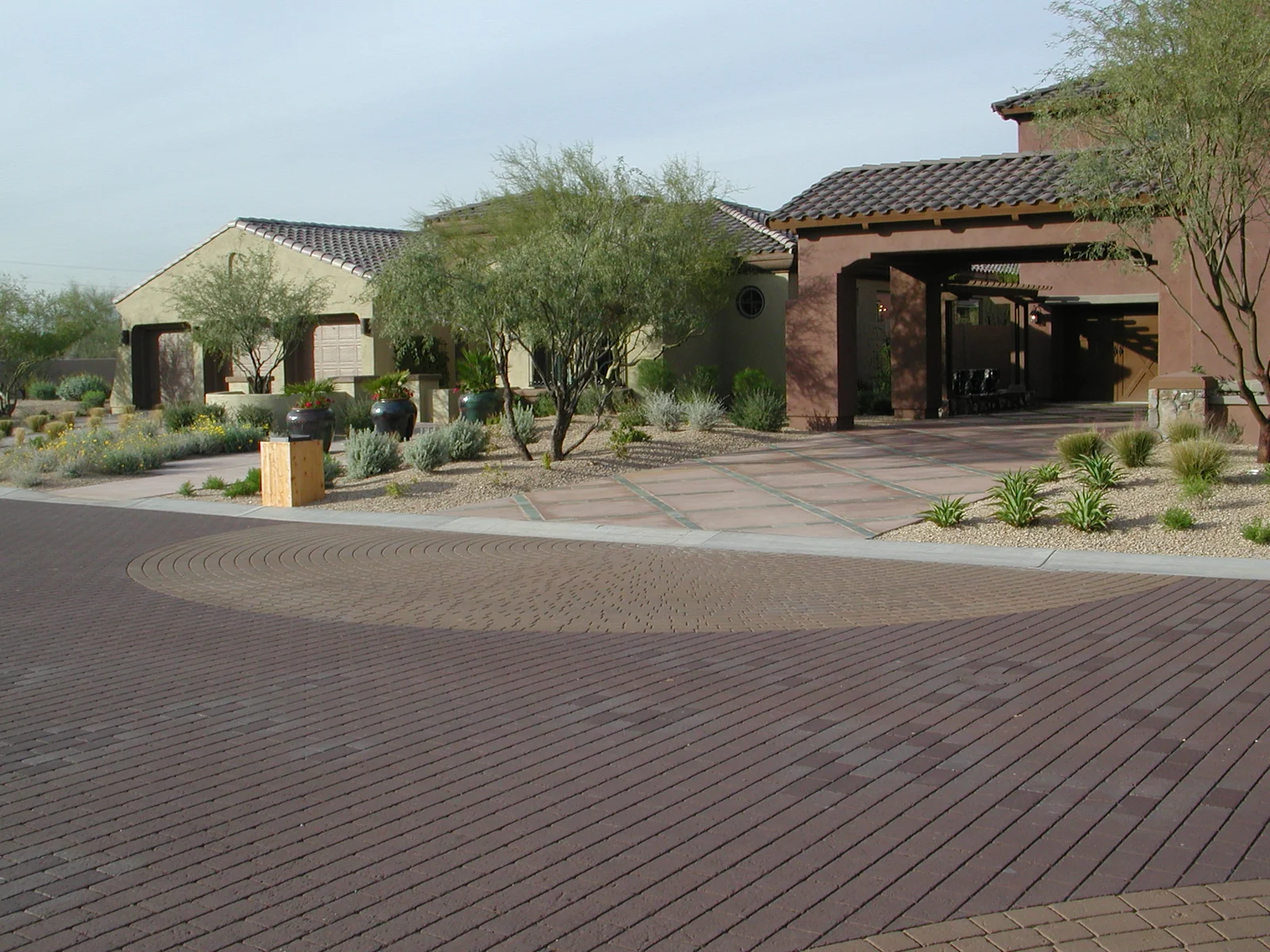Decorative patterned asphalt with a circular accent in a landscaped plaza; an Asphatec family example, not a confirmed AsphaStamp installation